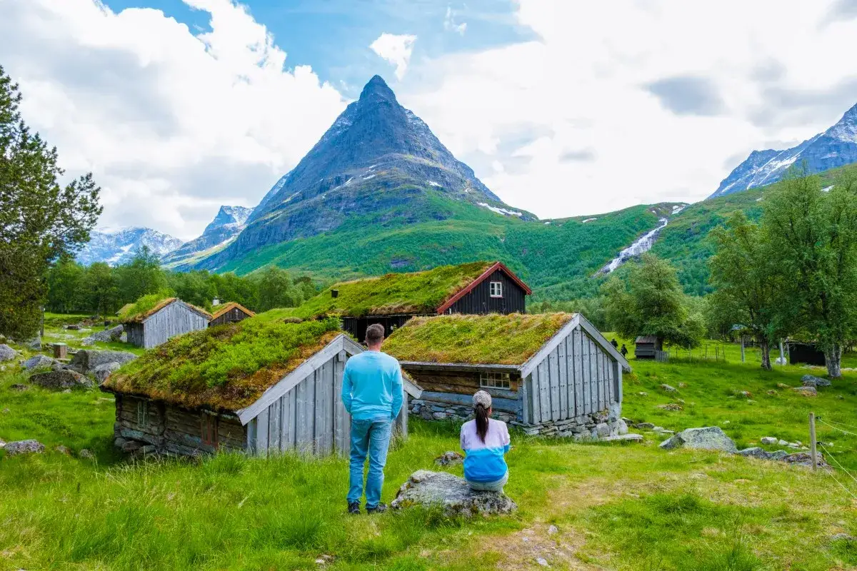 Para podróżników podziwia norweskie chatki z zielonymi dachami i górski krajobraz. Czy do Norwegii potrzebny jest paszport? Sprawdź przed wyjazdem!