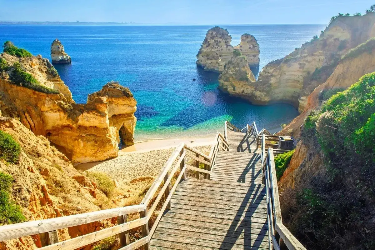 Malownicze portugalia plaże z klifami i turkusową wodą. Drewniane schody prowadzą do ukrytej zatoczki.