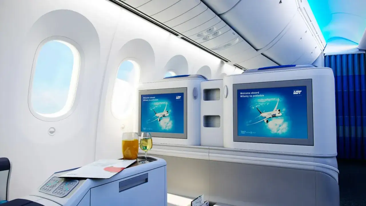Luksusowy Dreamliner LOT-u w locie. Na ekranach powitalne grafiki, obok napoje.