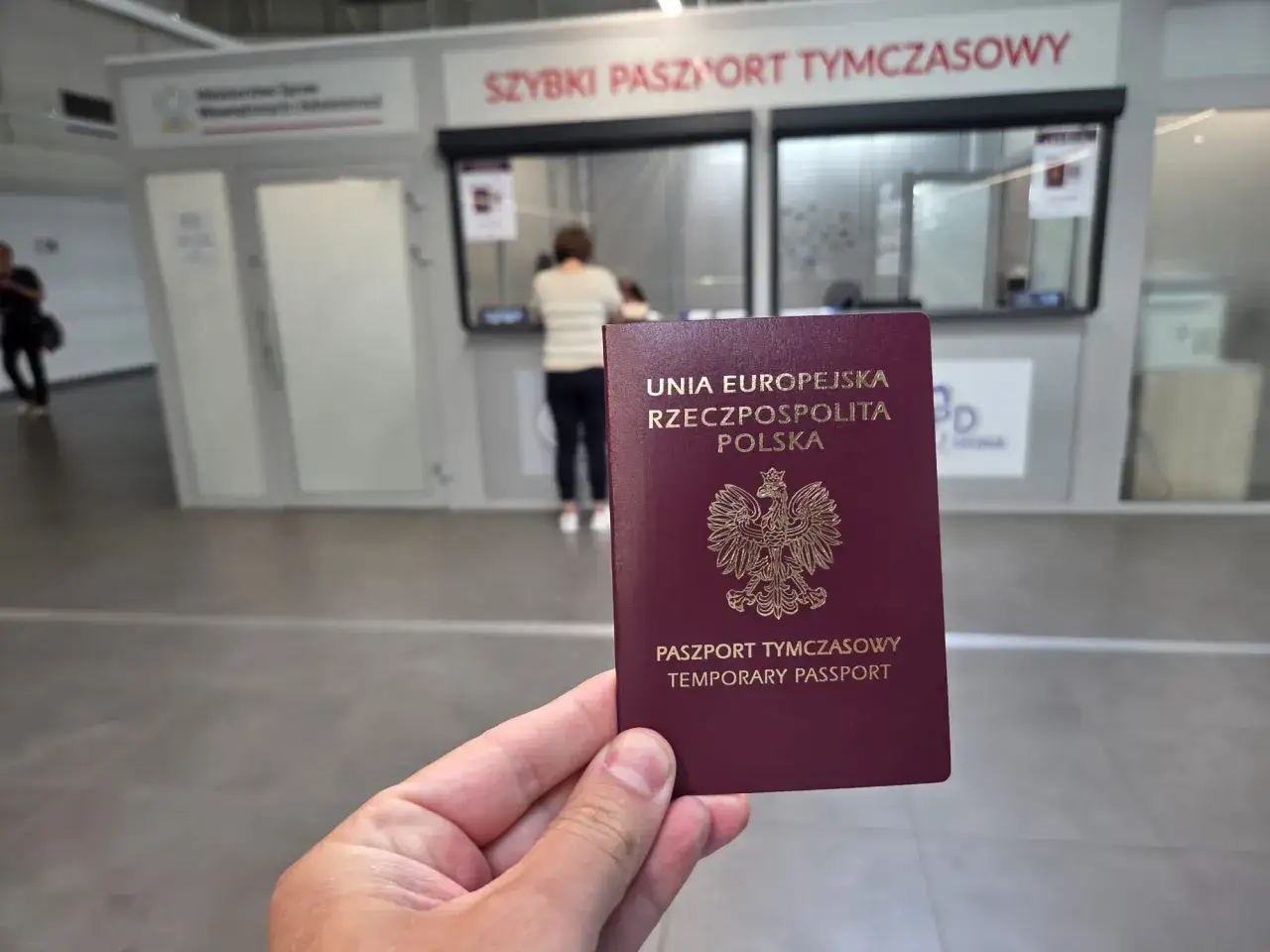 Ważny dowód przed wylotem to paszport tymczasowy. W tle okienko urzędu paszportowego.
