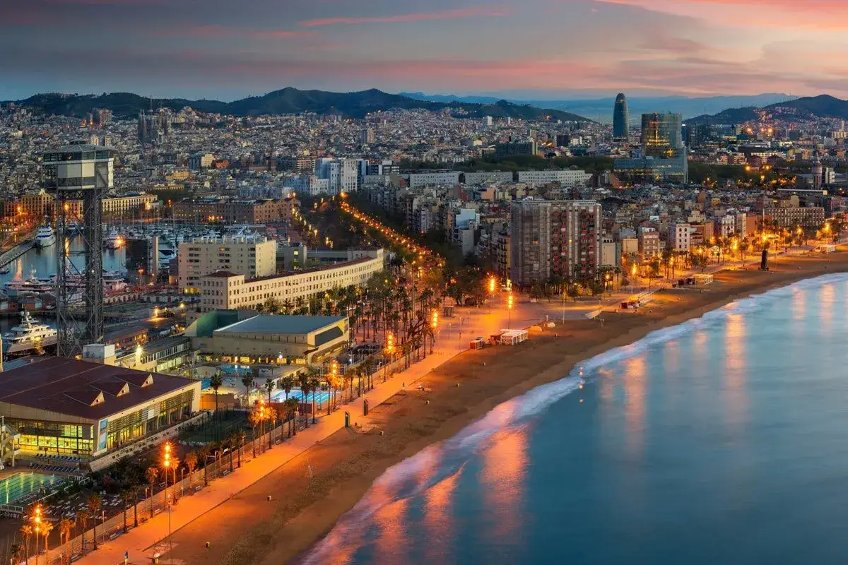 Zachód słońca nad Barceloną, idealne miejsce na wakacje w Hiszpanii. Widok na plażę, port i miasto.
