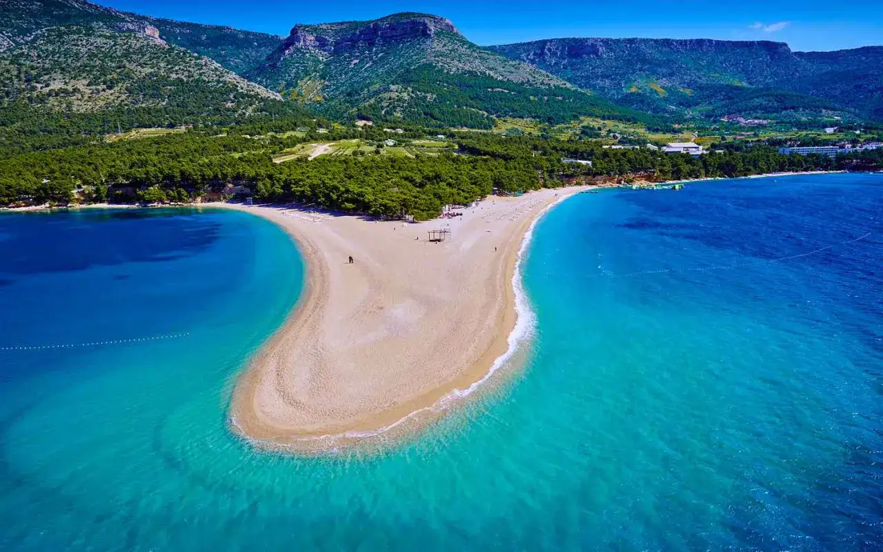 Zlatni Rat, jedna z najładniejszych plaż w Chorwacji, rozpościera się w kształcie rogu obfitości, otoczona turkusowym morzem i zielonymi wzgórzami.