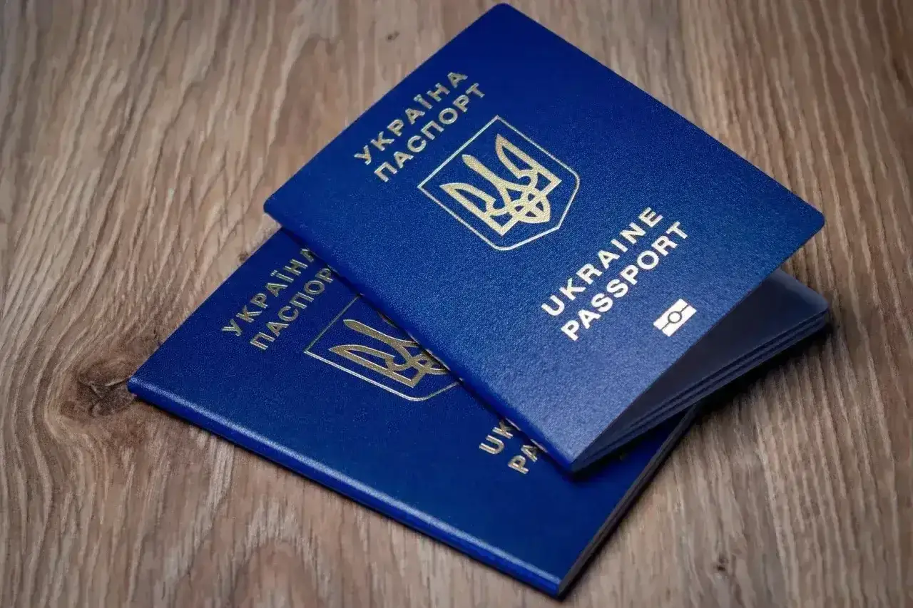 Dwa niebieskie paszporty Ukrainy leżą na drewnianym blacie. Planujesz podróż? Sprawdź, czy do Turcji potrzebna jest wiza.