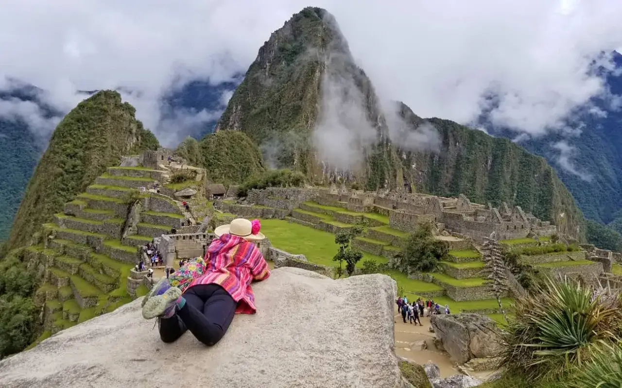 Osoba w kapeluszu leży na skale, podziwiając ruiny Machu Picchu. To wymarzone miejsce w ciepłych krajach, gdzie historia splata się z naturą.