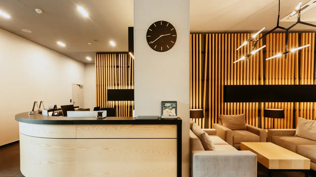 Nowoczesne recepcja i strefa wypoczynkowa w hotelach dla dorosłych. Drewniane akcenty, wygodne sofy i stylowe oświetlenie tworzą przytulną atmosferę.