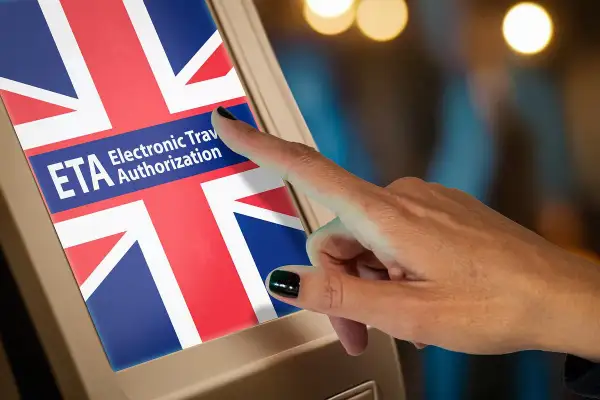 Dłoń dotyka ekranu z flagą Wielkiej Brytanii i napisem ETA Electronic Travel Authorization. To krok do uzyskania wizy do Anglii.
