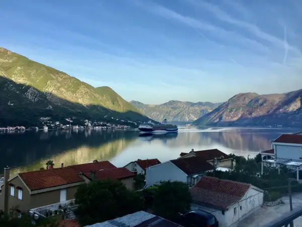 Widok na zatokę w Czarnogórze z górami w tle i statkiem wycieczkowym. Czy Czarnogóra jest bezpieczna? Tak, to spokojne miejsce na wakacje.