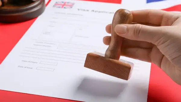 Pieczątka nad dokumentem "Visa Application" z flagą Wielkiej Brytanii. Szykuje się wiza do Londynu.