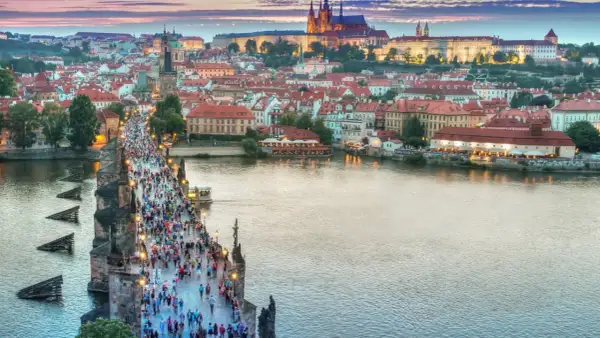 Praga nocą, tłumy na Moście Karola. Idealne miejsce na tanie wycieczki objazdowe po Europie.