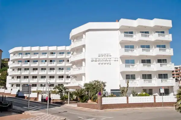 Hotel Bernat II, idealny na wakacje all inclusive w Barcelonie. Biały budynek z balkonami i widokiem na morze.