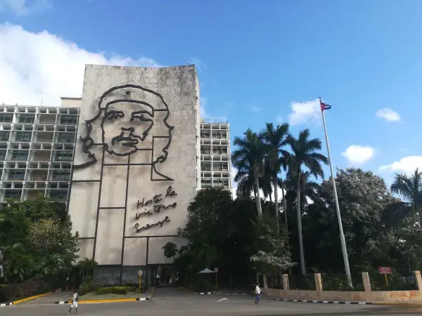 Monumentalny portret Che Guevary zdobi budynek w Hawanie, stolicy Kuby. Obok palm i kubańska flaga.
